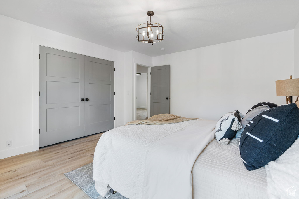 Bedroom with a notable chandelier and light wood-type flooring