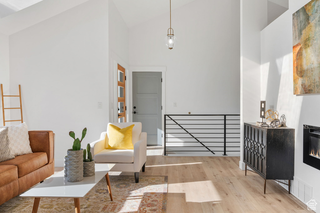 Living room with light hardwood / wood-style floors and high vaulted ceiling