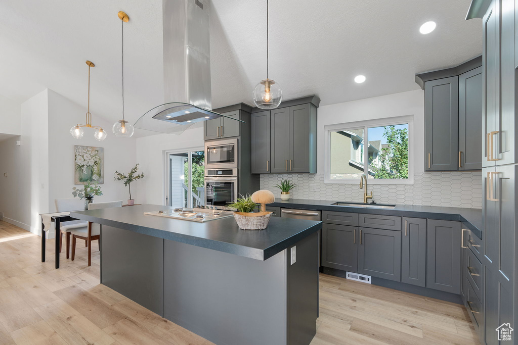 Kitchen featuring light hardwood / wood-style flooring, stainless steel appliances, decorative light fixtures, and sink