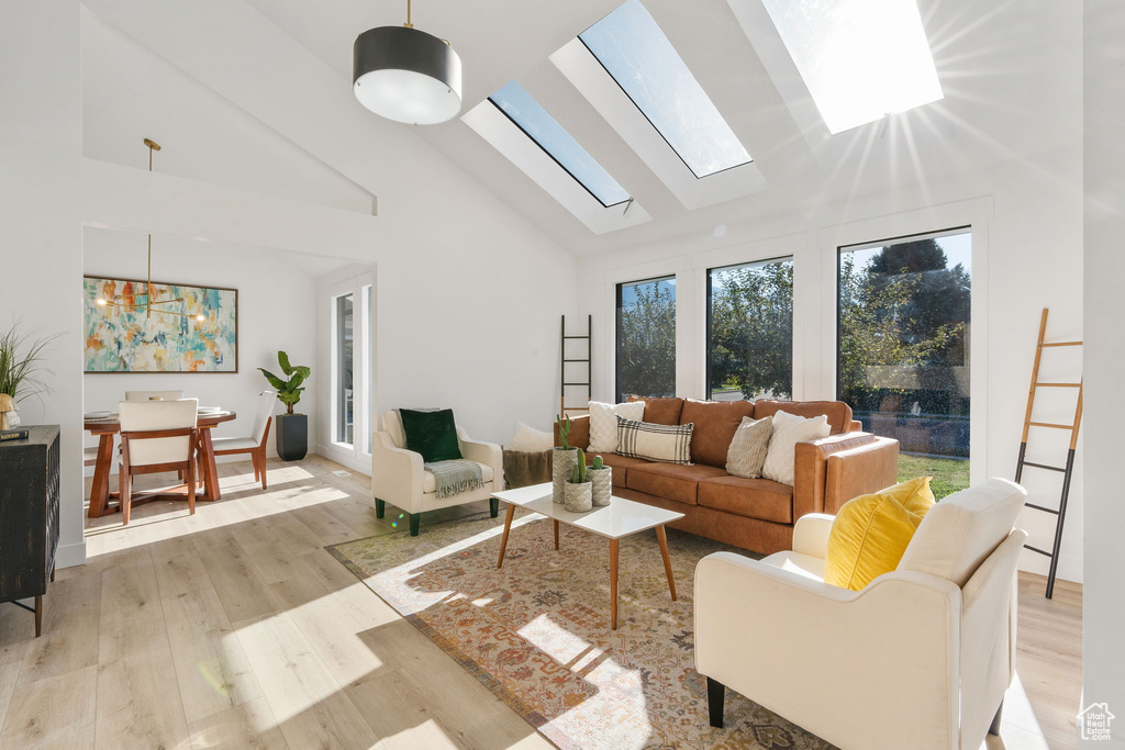 Living room featuring a skylight, light hardwood / wood-style floors, and high vaulted ceiling