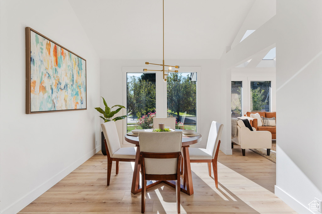 Dining space with an inviting chandelier, lofted ceiling, and light hardwood / wood-style floors