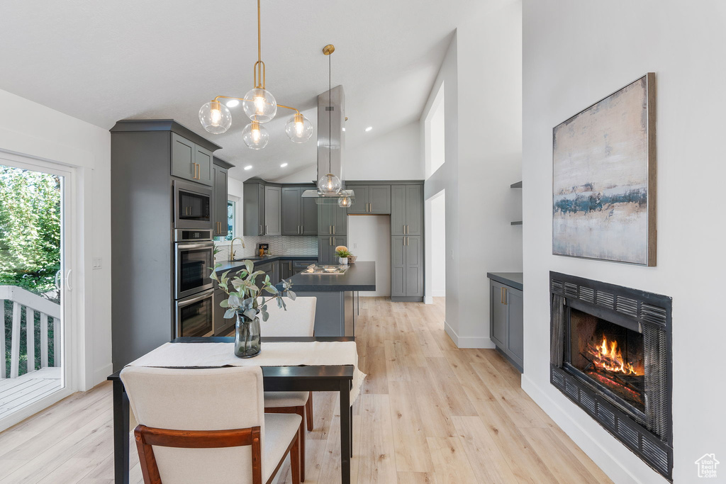 Dining area with sink, light hardwood / wood-style floors, and high vaulted ceiling