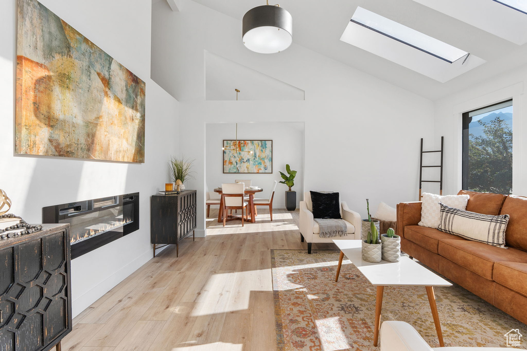 Living room featuring vaulted ceiling with skylight and light hardwood / wood-style flooring