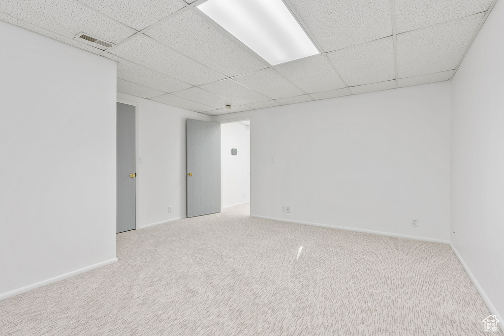 Empty room featuring carpet floors and a paneled ceiling