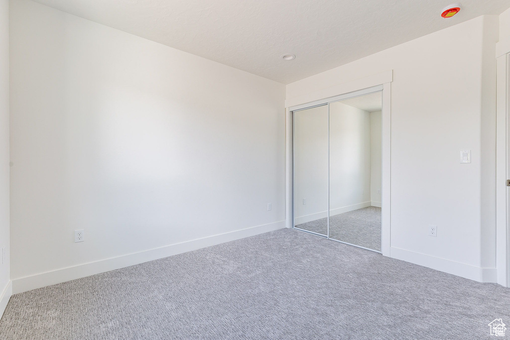 Unfurnished bedroom with carpet and a closet