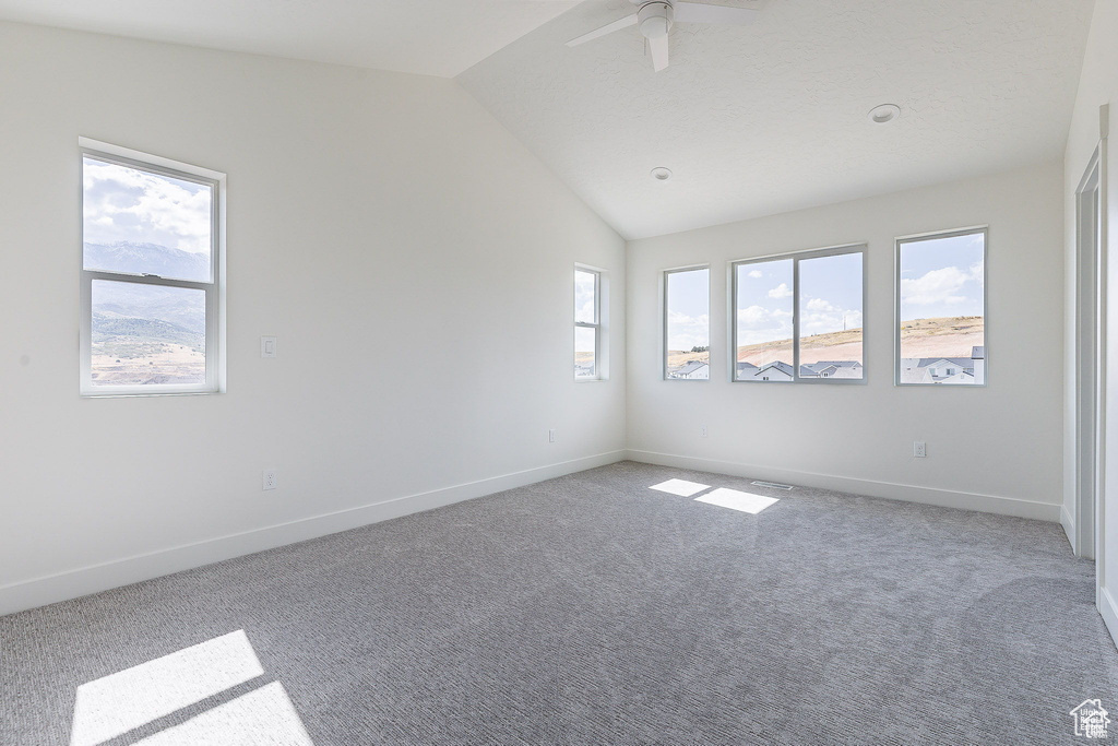 Spare room featuring lofted ceiling, ceiling fan, and carpet flooring