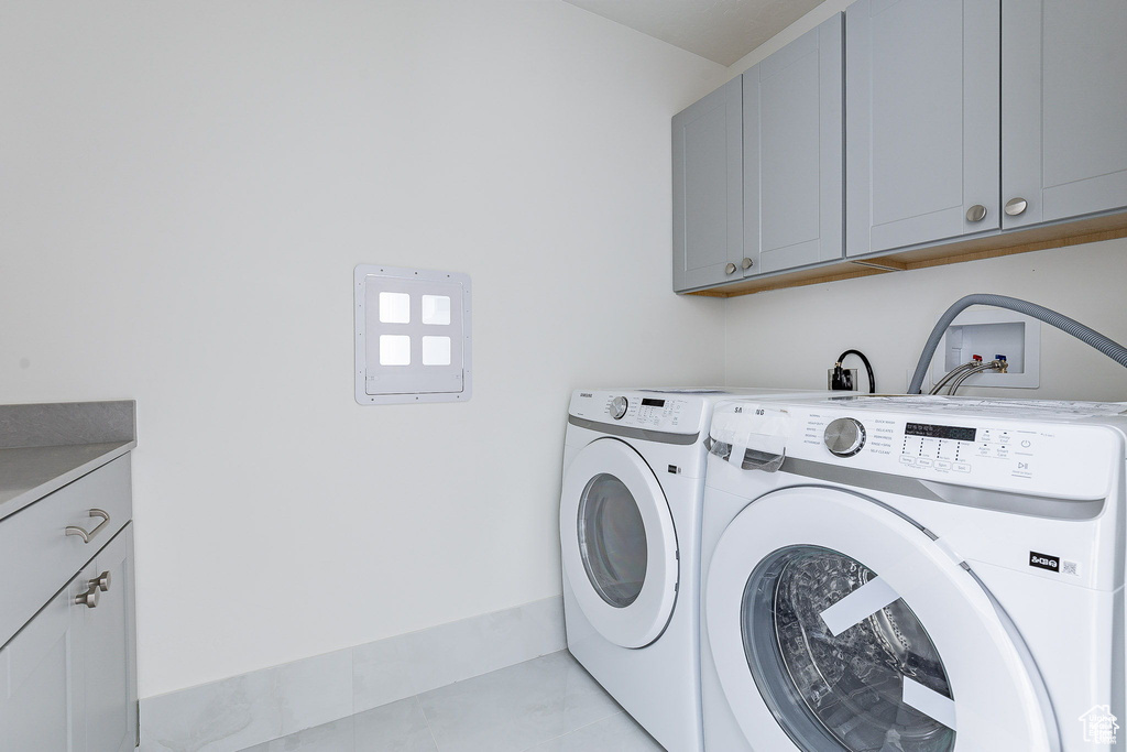 Clothes washing area featuring cabinets, light tile patterned floors, and separate washer and dryer