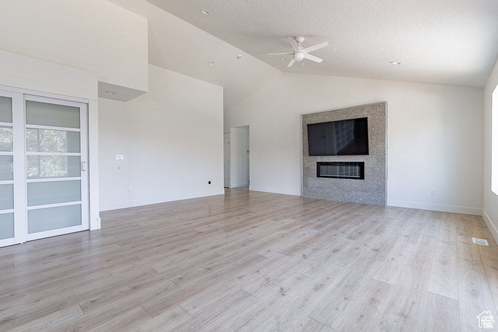 Unfurnished living room with ceiling fan, light hardwood / wood-style flooring, and vaulted ceiling