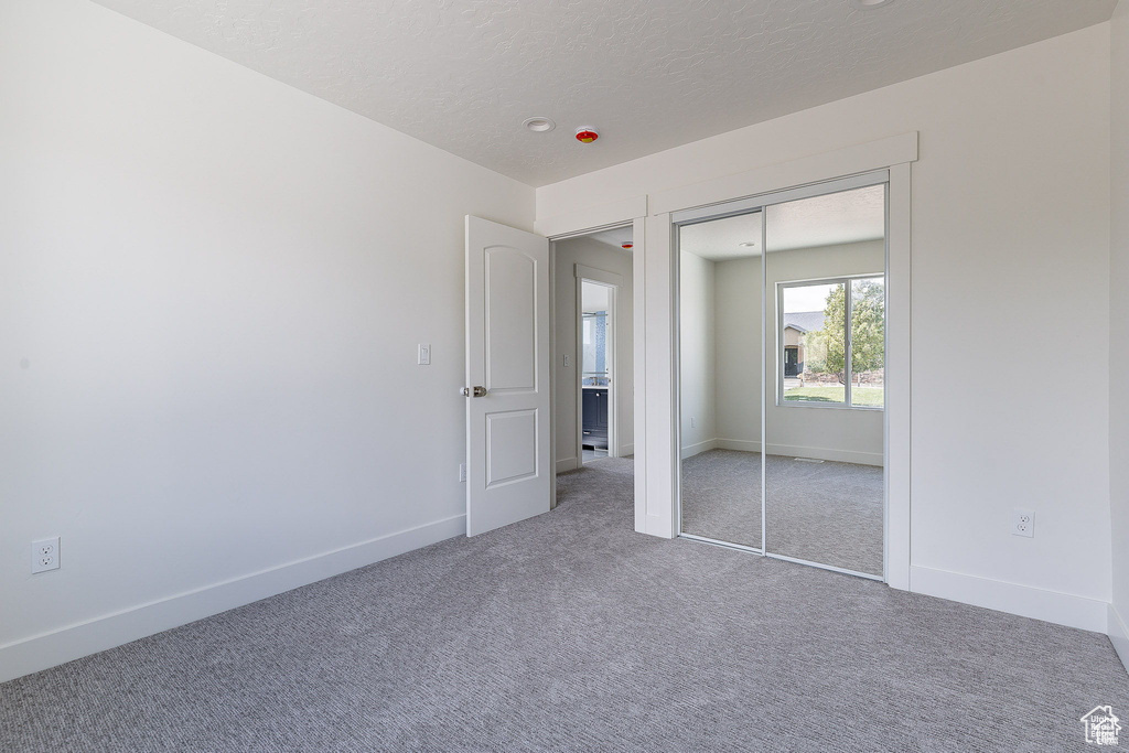 Unfurnished bedroom featuring carpet flooring and a closet