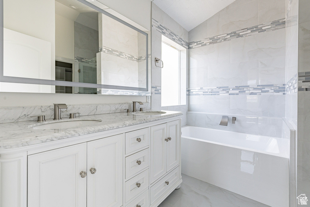 Bathroom with vaulted ceiling, vanity, and a bathing tub