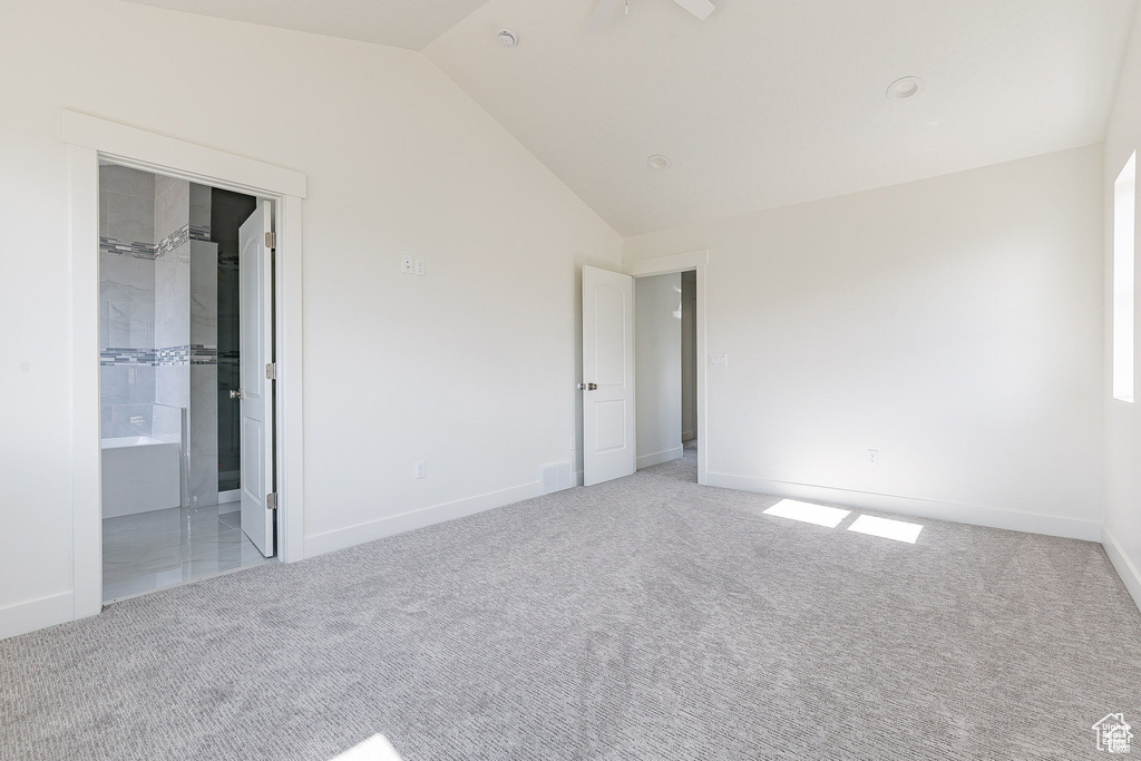 Unfurnished bedroom with lofted ceiling, ensuite bath, and light carpet