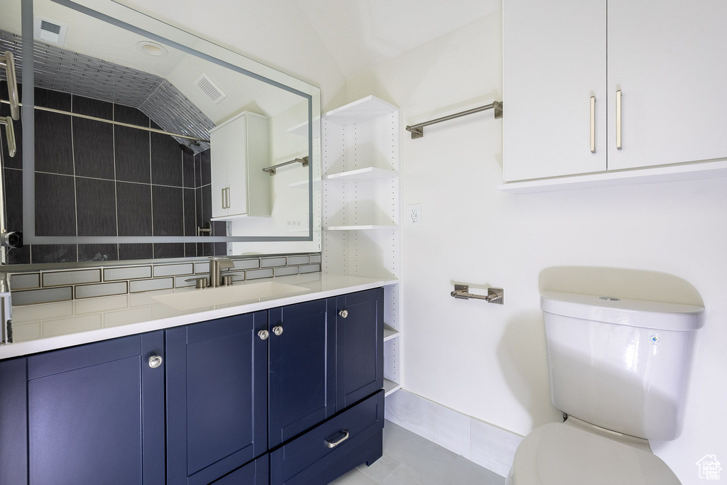 Bathroom featuring lofted ceiling, vanity, and toilet