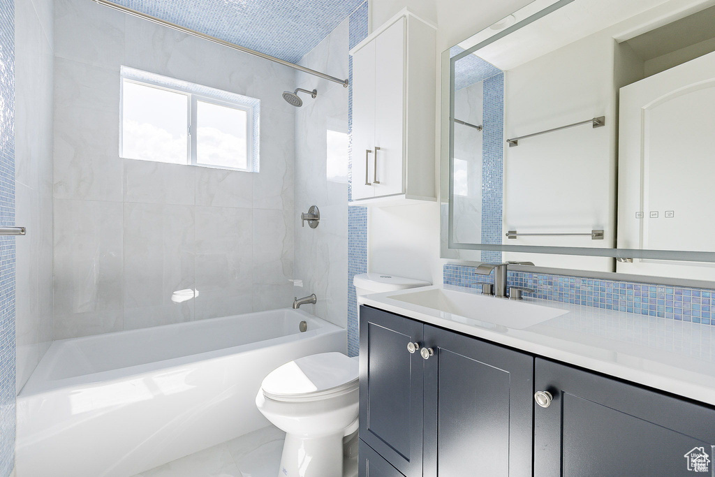 Full bathroom featuring tiled shower / bath, vanity, toilet, and decorative backsplash