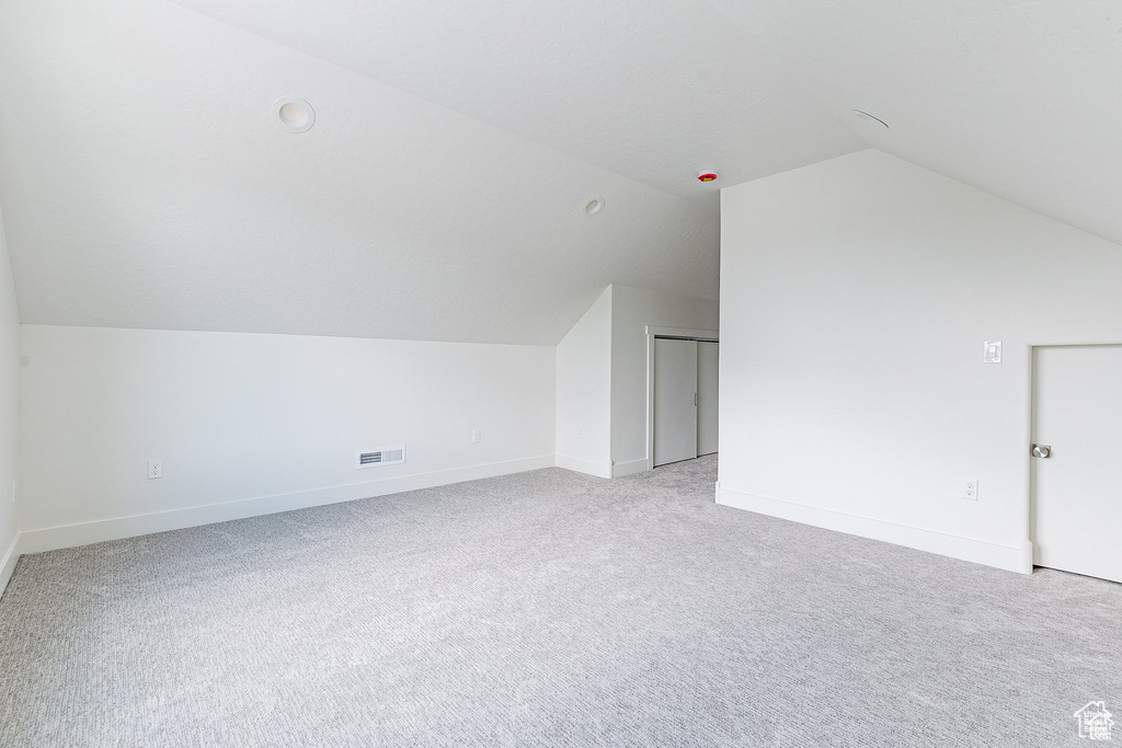 Bonus room featuring vaulted ceiling and light carpet