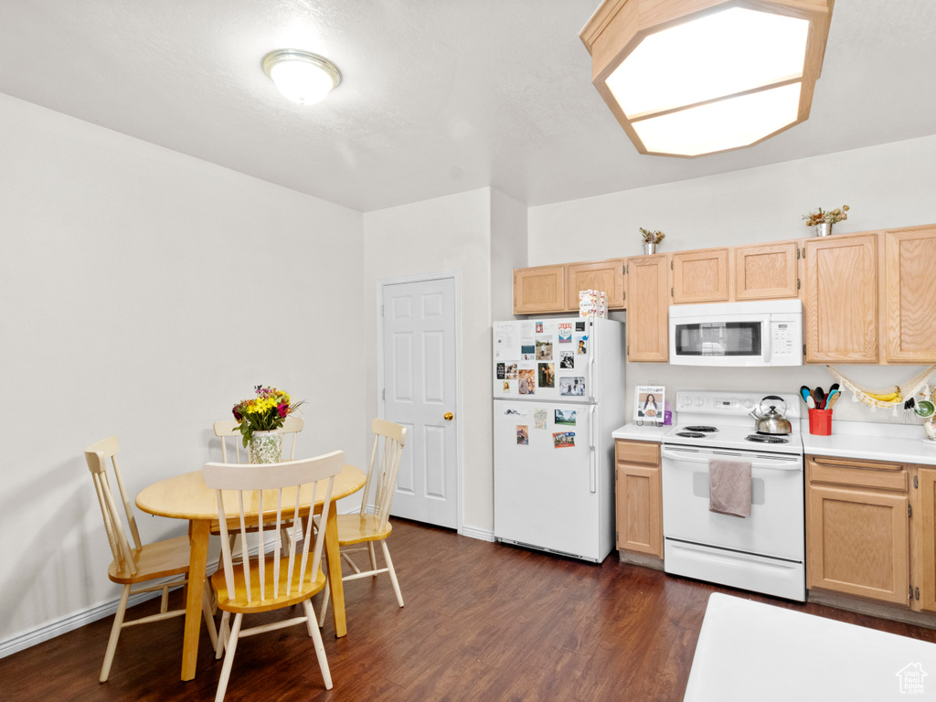 Kitchen with dark hardwood / wood-style floors, white appliances, and light brown cabinets