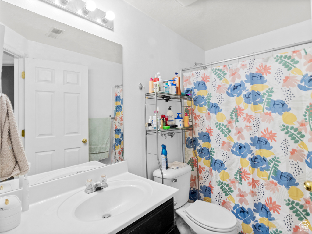 Bathroom with vanity, toilet, and a shower with shower curtain