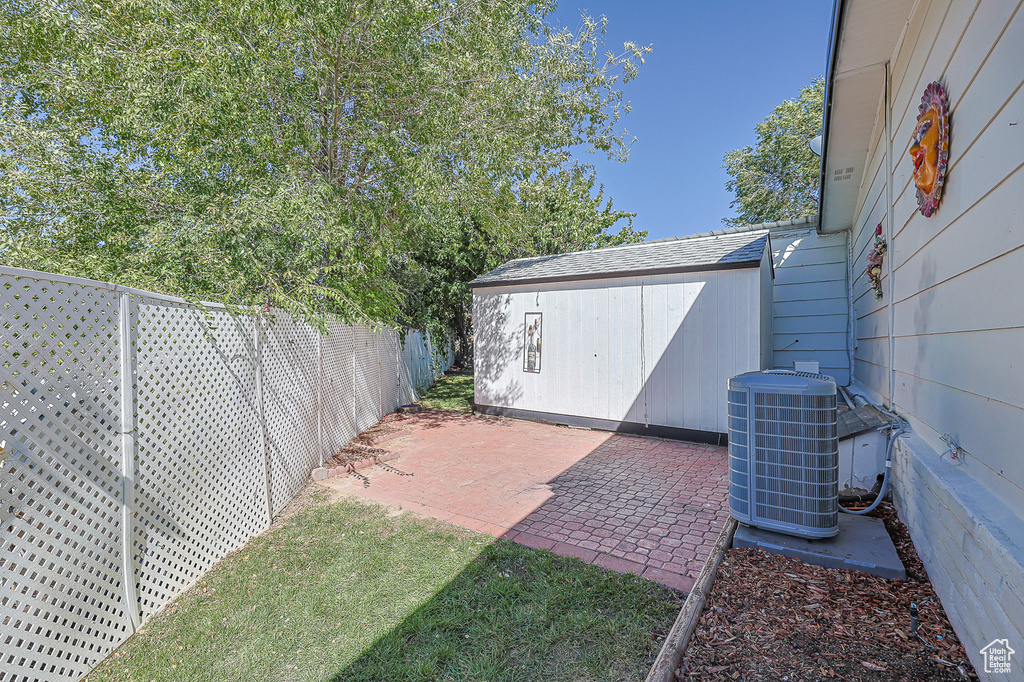 View of yard featuring a storage shed, central air condition unit, and a patio area