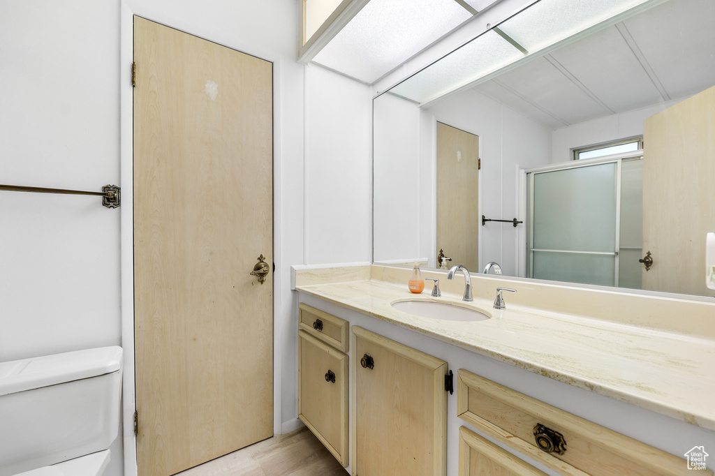 Bathroom with hardwood / wood-style flooring, walk in shower, vanity, and toilet