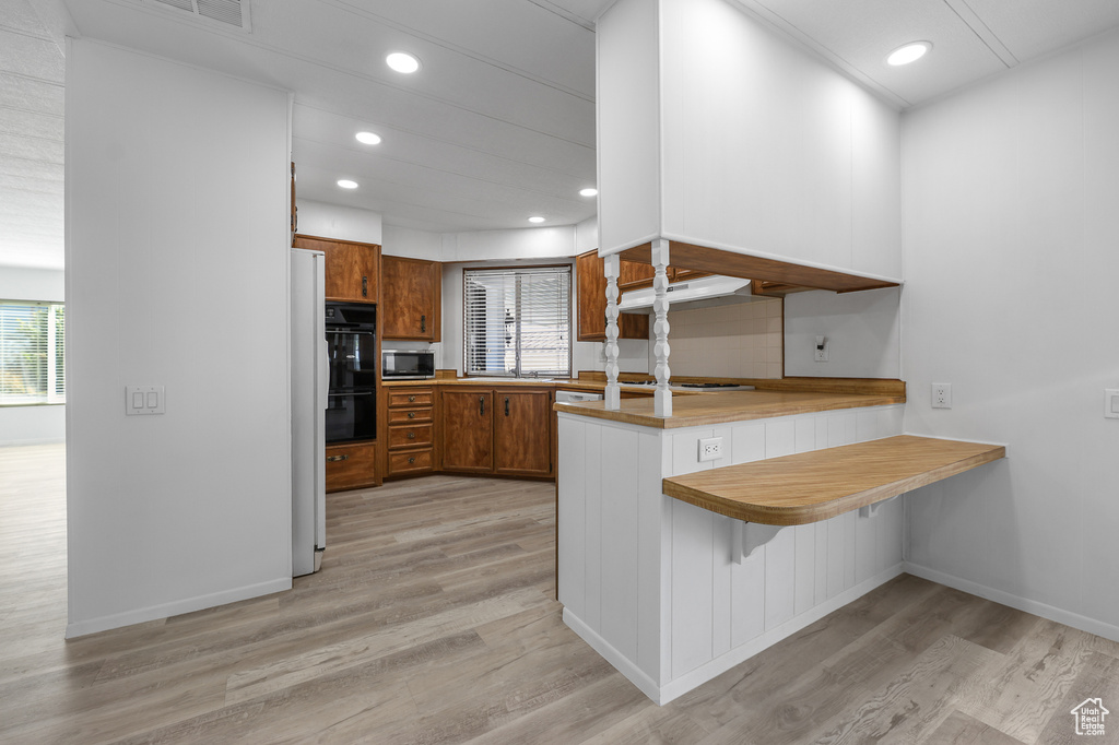 Kitchen with light wood-type flooring, kitchen peninsula, and a breakfast bar area