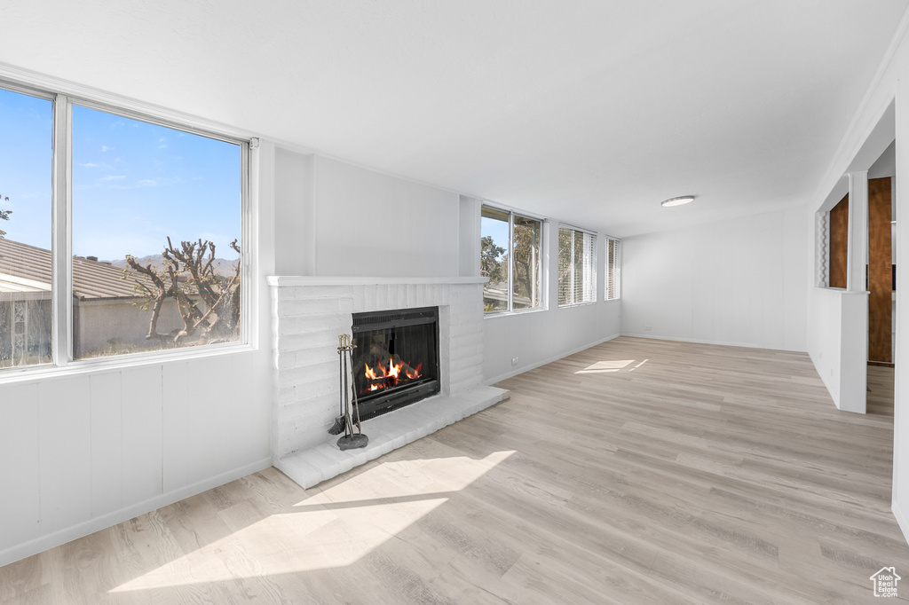 Unfurnished living room featuring light wood-type flooring and a fireplace