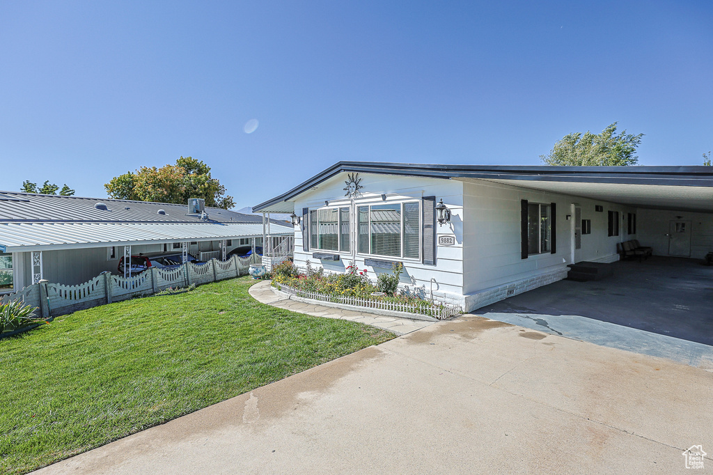 View of property exterior with a lawn and a carport