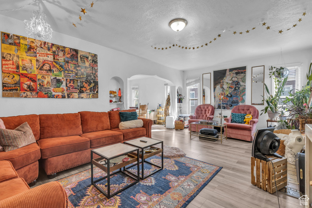 Living room featuring a notable chandelier, a textured ceiling, and light hardwood / wood-style floors