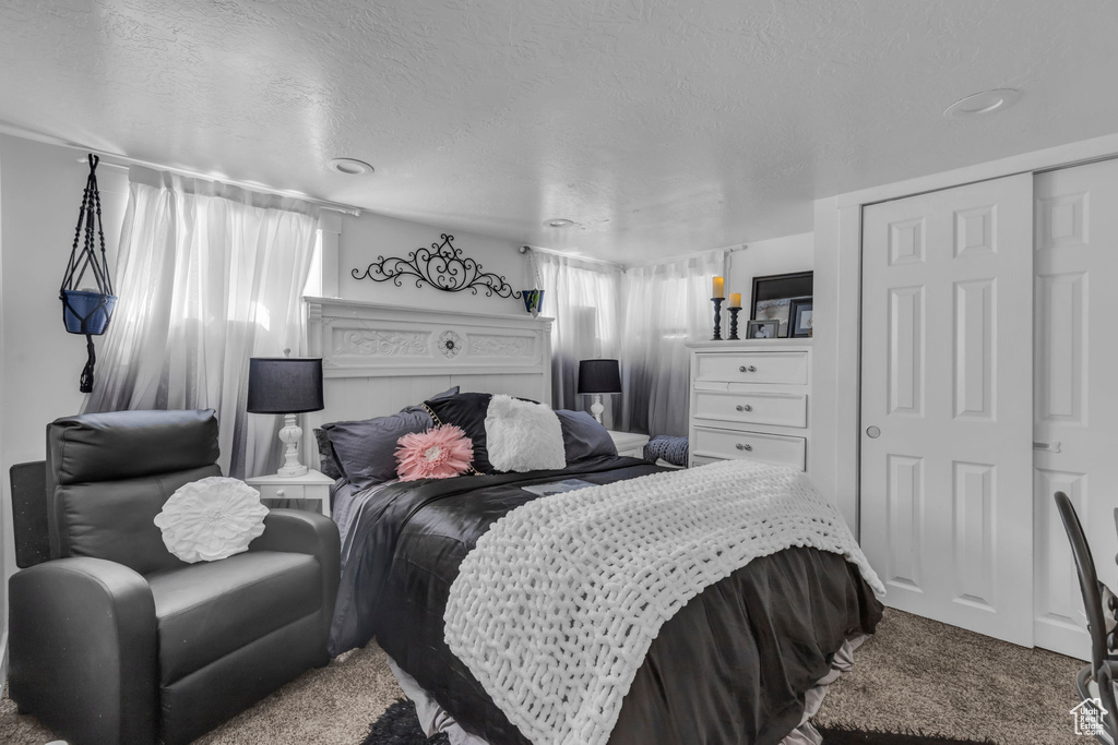 Bedroom with a closet, a textured ceiling, and carpet flooring