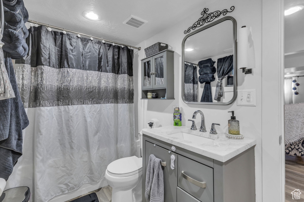 Bathroom featuring walk in shower, vanity, hardwood / wood-style floors, and toilet