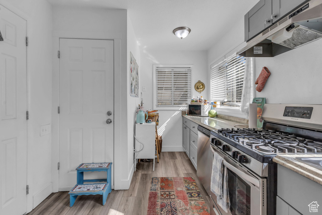 Kitchen featuring light hardwood / wood-style flooring, stainless steel gas range, and gray cabinetry