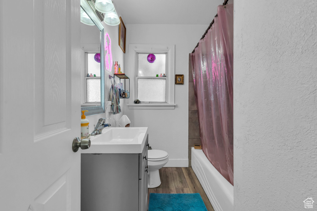 Full bathroom featuring vanity, toilet, shower / bath combo with shower curtain, and hardwood / wood-style flooring