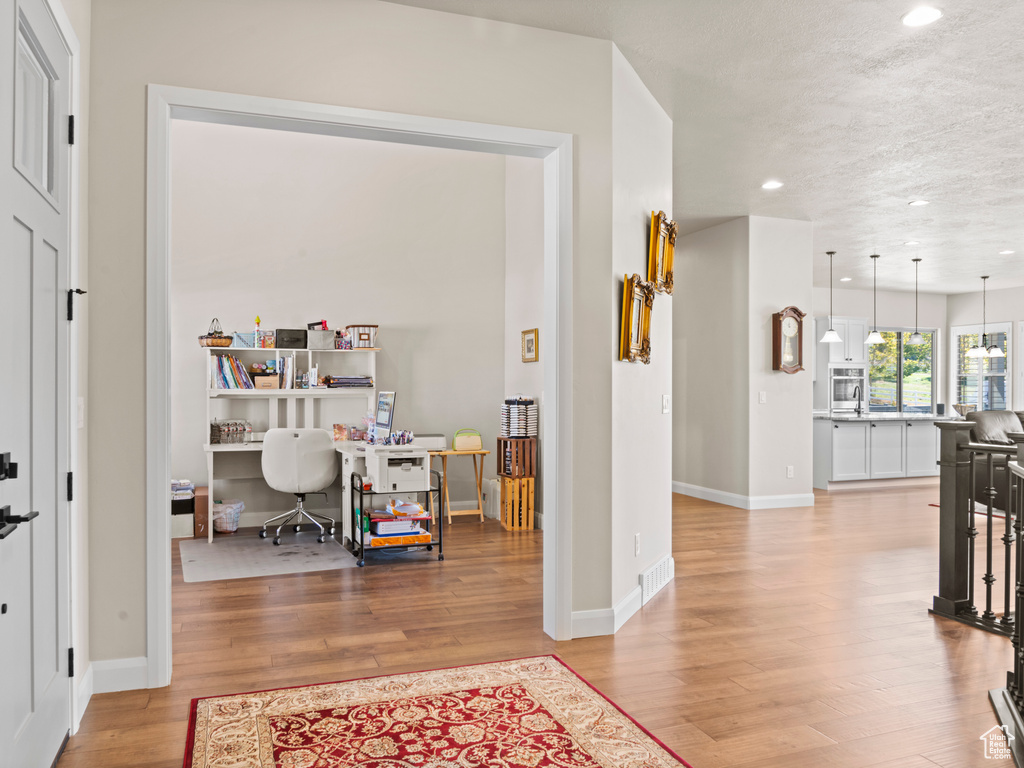 Interior space with a textured ceiling and light hardwood / wood-style flooring