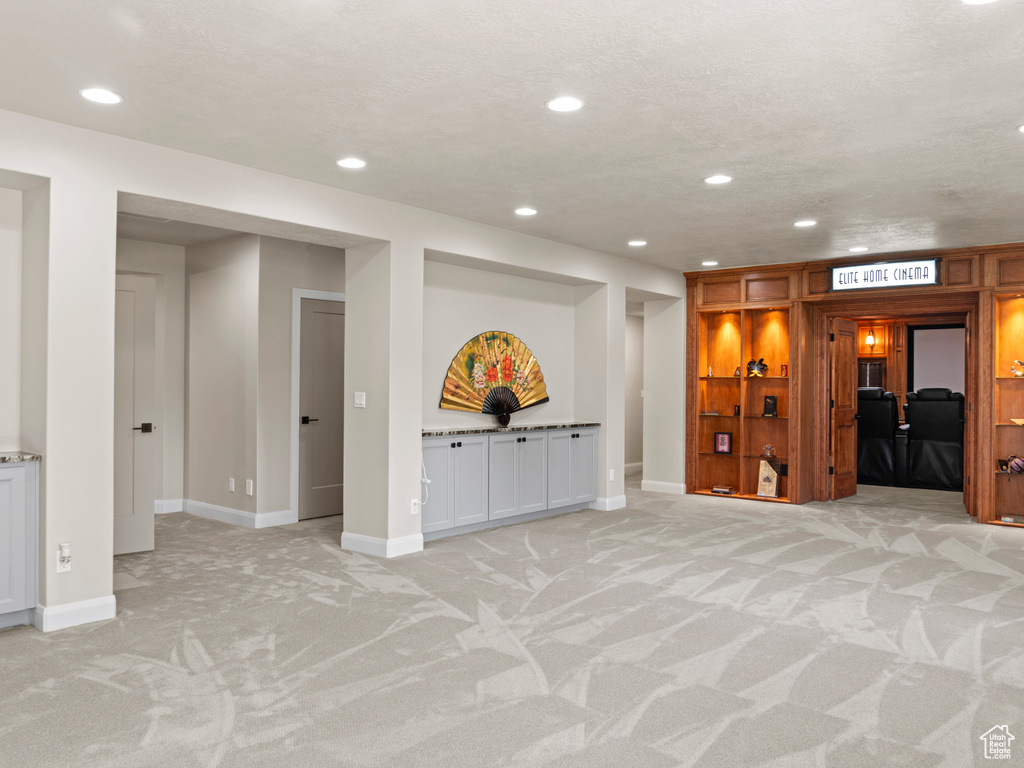 Basement featuring light colored carpet and a textured ceiling