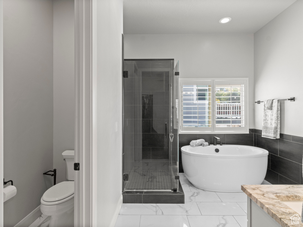 Full bathroom featuring tile walls, shower with separate bathtub, vanity, and toilet