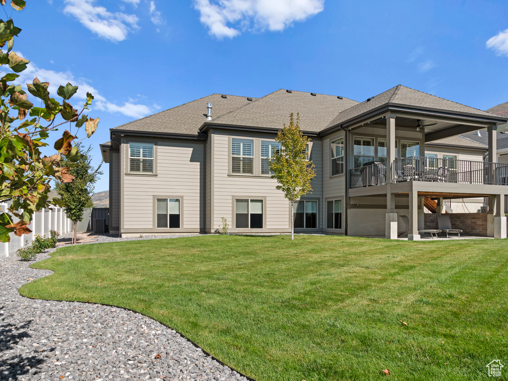 Rear view of property with ceiling fan, a deck, a lawn, and a patio