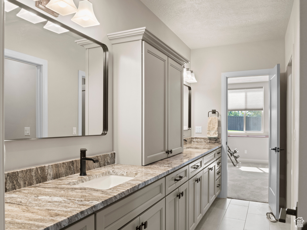 Bathroom featuring a tub, vanity, a textured ceiling, and tile patterned floors