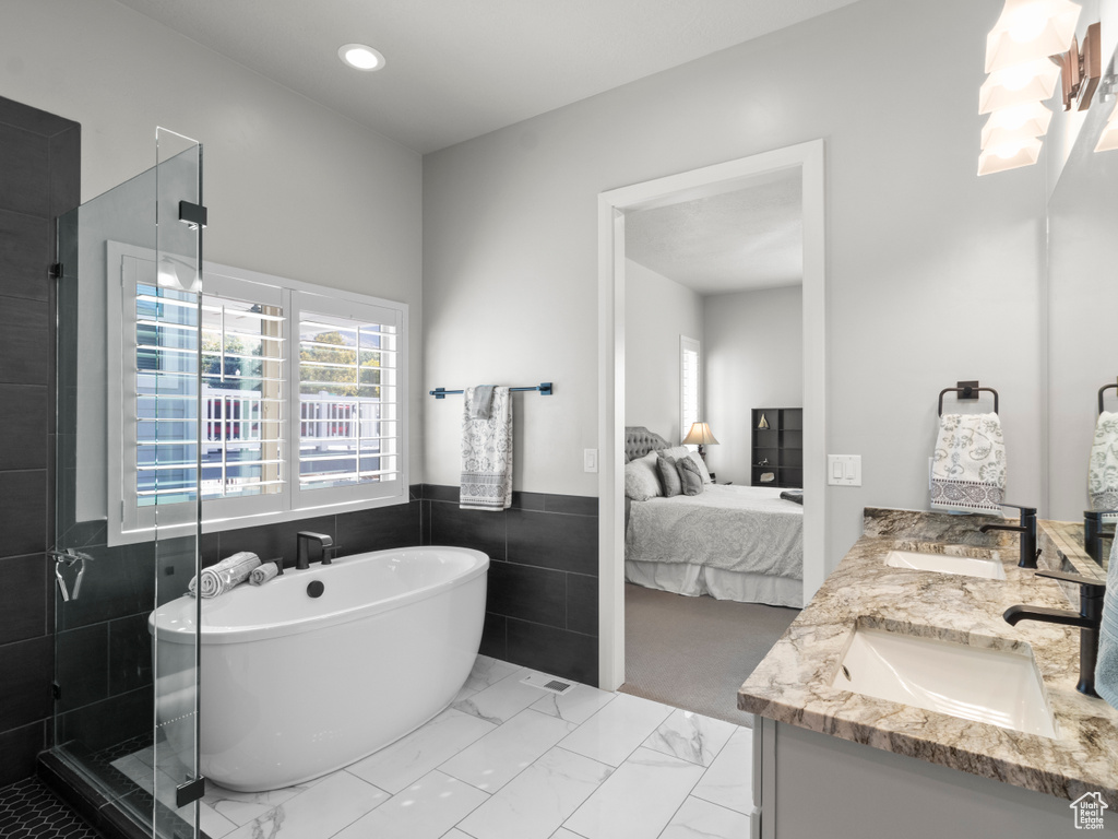 Bathroom featuring tile walls, independent shower and bath, and vanity