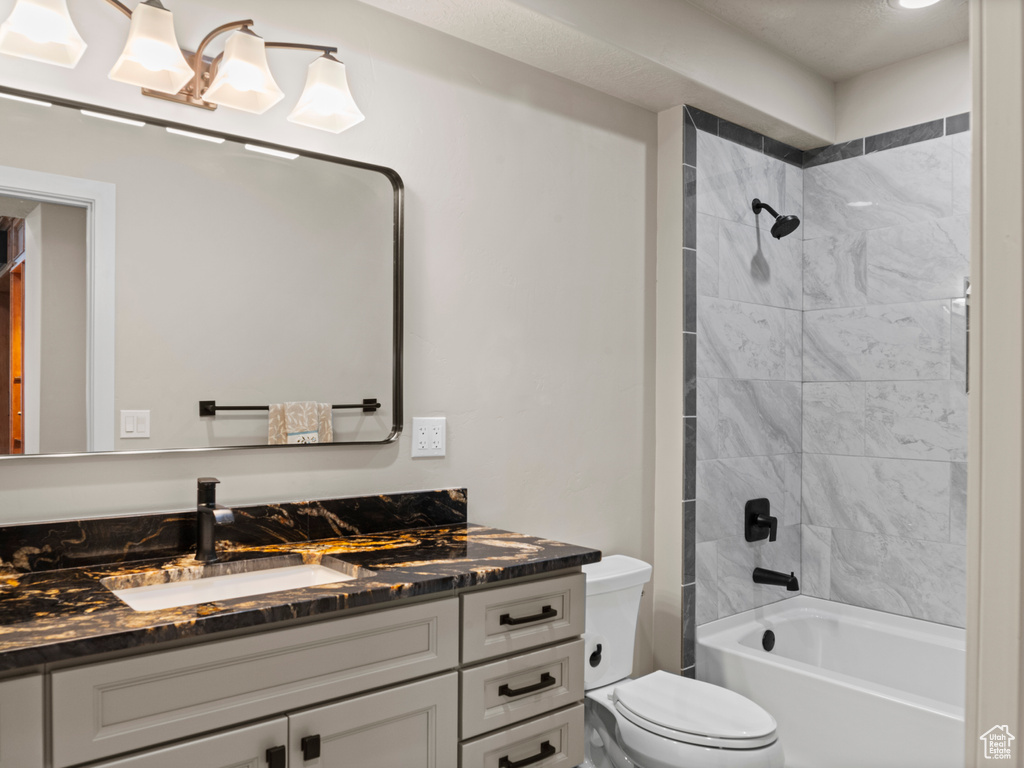 Full bathroom with tiled shower / bath, vanity, and toilet