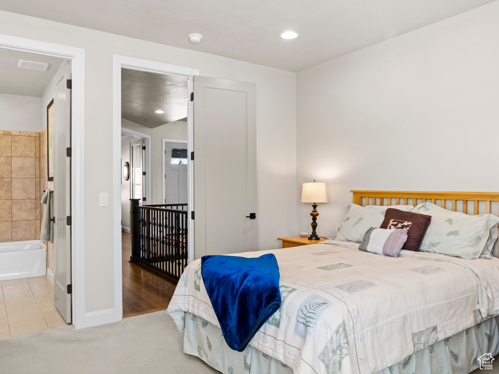 Bedroom with light hardwood / wood-style floors and ensuite bathroom