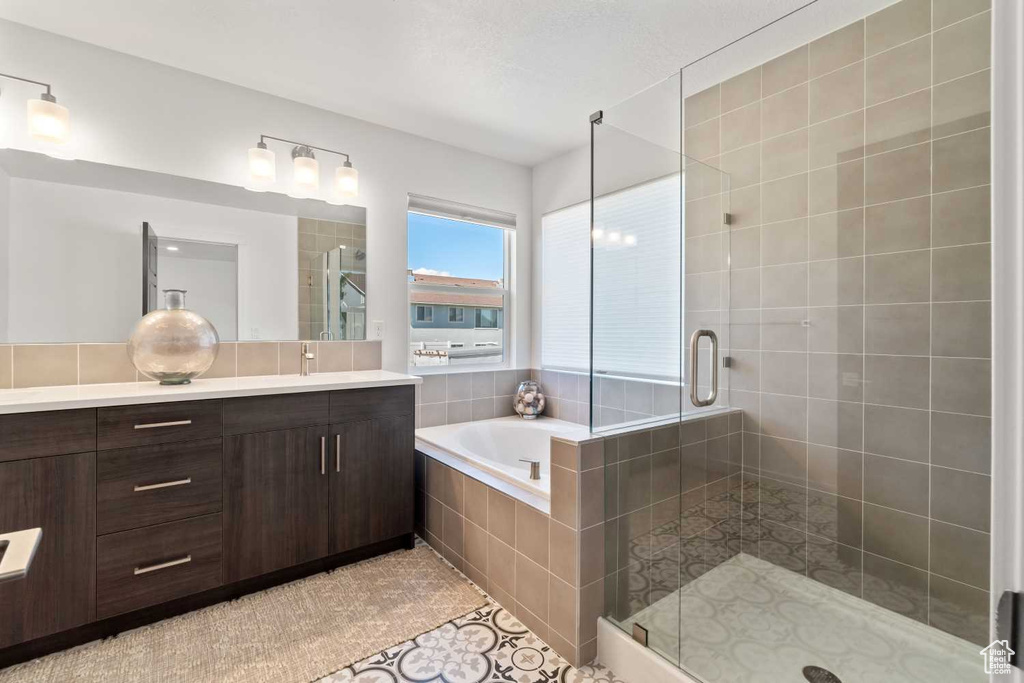 Bathroom with tile patterned flooring, vanity, and plus walk in shower