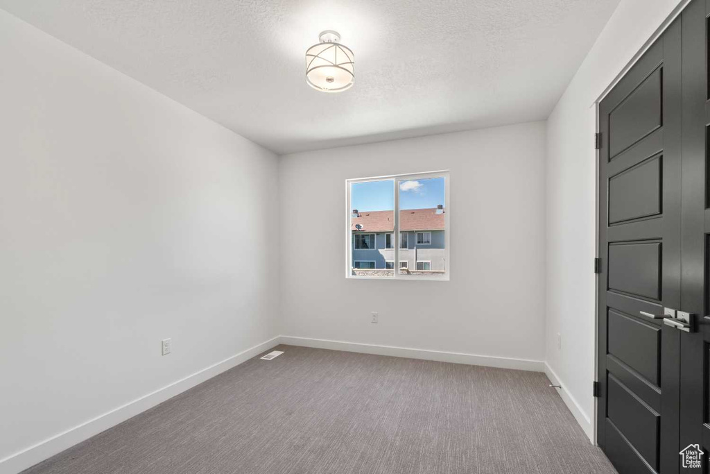 Empty room with carpet floors and a textured ceiling