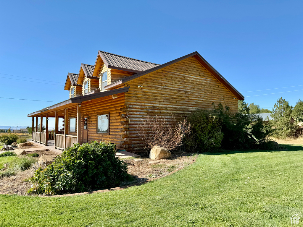 View of property exterior featuring a lawn and a porch