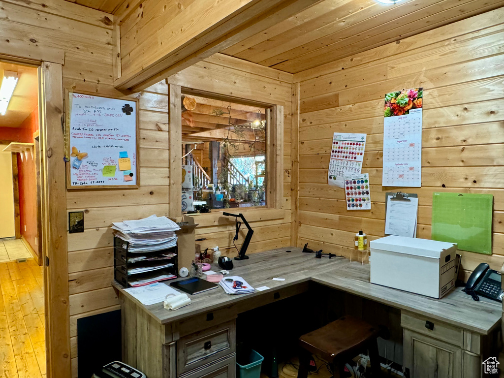 Office with light hardwood / wood-style floors and wood walls