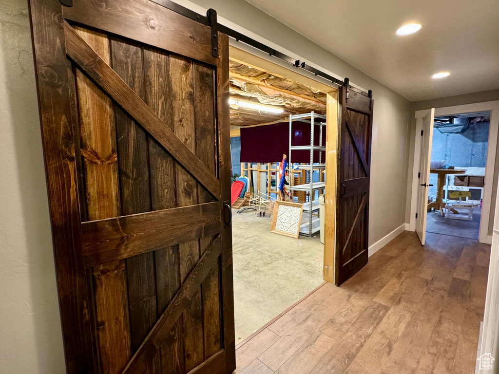 Hallway with wood-type flooring and a barn door