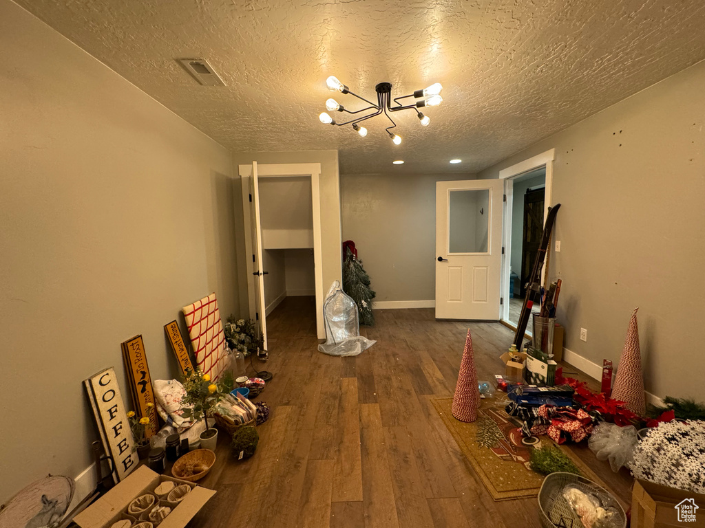 Corridor with a notable chandelier, a textured ceiling, and hardwood / wood-style floors