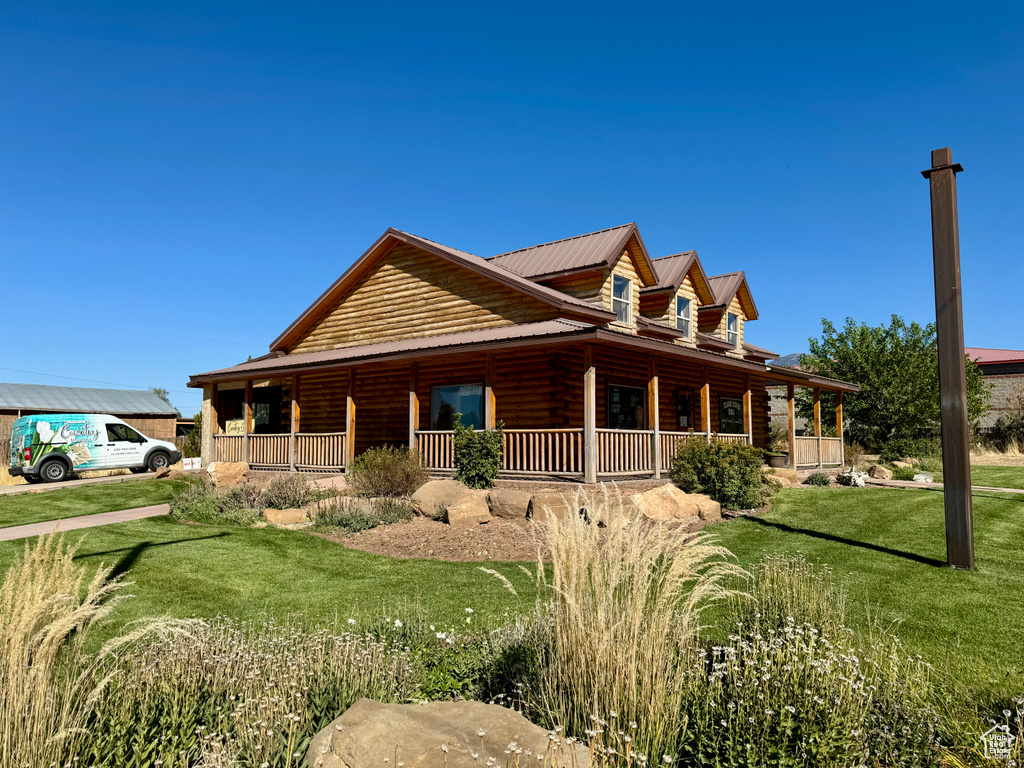 View of side of property with a yard and covered porch