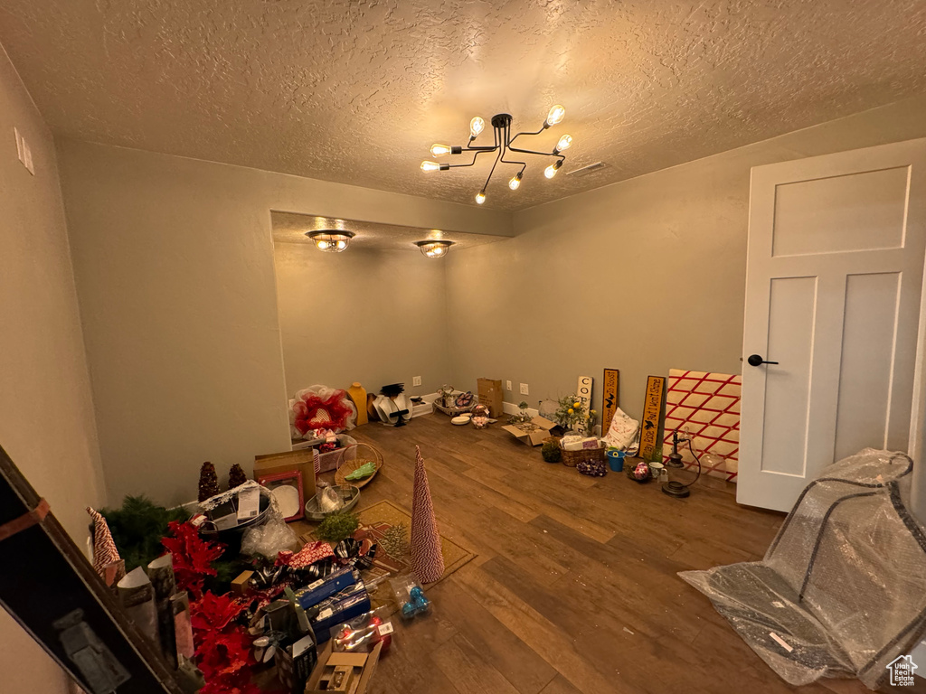 Misc room featuring a notable chandelier, wood-type flooring, and a textured ceiling