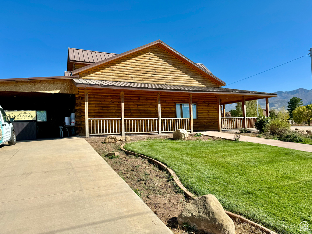 Log-style house with a carport, a front lawn, a mountain view, and covered porch