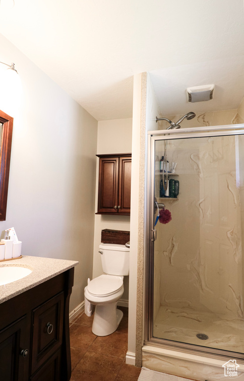 Bathroom with vanity, toilet, an enclosed shower, and tile patterned floors