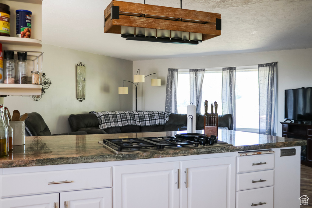 Kitchen with wood-type flooring, white cabinetry, and stainless steel gas cooktop