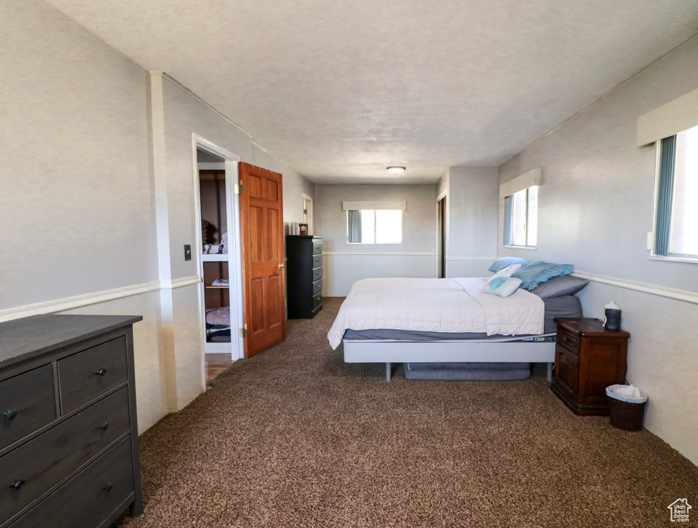 Bedroom with a textured ceiling and dark colored carpet